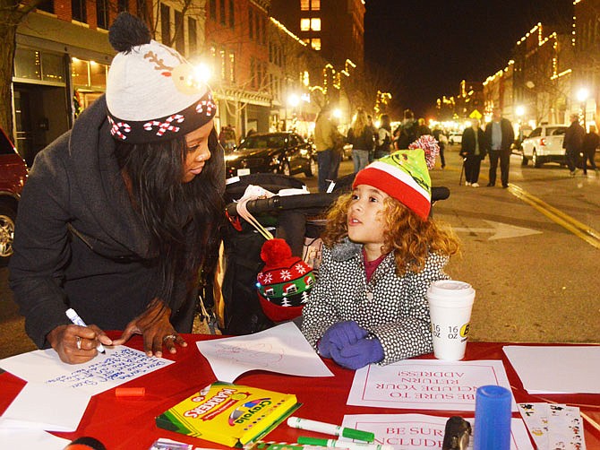 Renee Alexander helps her daughter Ella, 5, compose a letter to Santa on Friday during Living Windows downtown. Thousands attended the pre-Christmas event as storefronts came alive with holiday themes.
