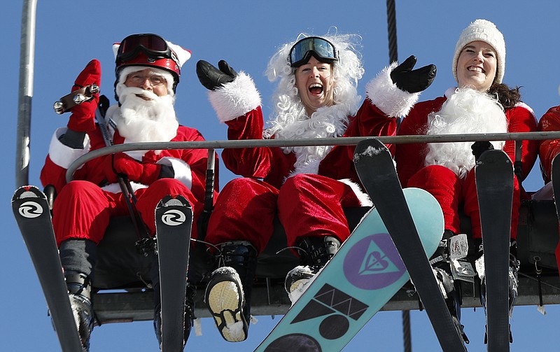 Skiers and a snowboarder dressed Santa Claus ride the chairlift at Sunday River during the ski resort's 18th annual Santa Sunday event, Sunday, Dec. 3, 2017, in Newry, Maine. In the name of charity, 160 skiing and snowboarding Santas raised $2,500 for the Sunday River Community Fund, a fund that benefits non-profits in area communities. (AP Photo/Robert F. Bukaty)