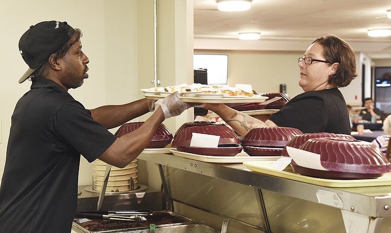 Julie Smith/News Tribune
Villa Marie food service worker Tyrone Seals, left, serves lunch, and restorative aide Jessica Lammers prepares to deliver it to residents. It’s becoming increasingly difficult for predominantly Medicaid-funded nursing homes to attract and retain quality personnel as the disparity in reimbursement rates increases. 