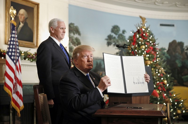 President Donald Trump, accompanied by Vice President Mike Pence, holds up a signed proclamation recognizing Jerusalem as the capital of Israel in the Diplomatic Reception Room of the White House, Wednesday, Dec. 6, 2017, in Washington.  (AP Photo/Alex Brandon)