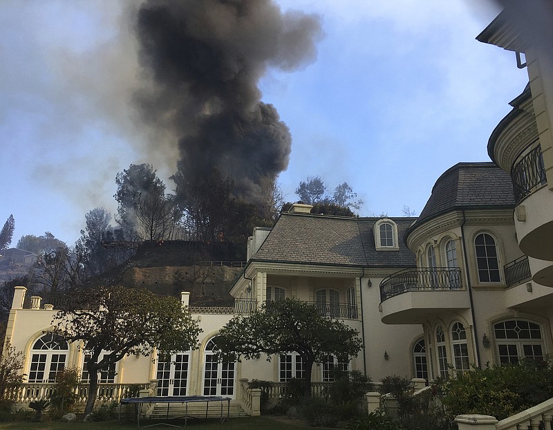 Flames from a wildfire work their way down a slope behind a home in the Bel Air district of Los Angeles Wednesday, Dec. 6, 2017. (AP Photo/Jae Hong)