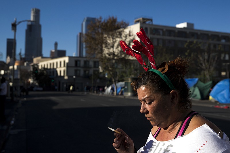 Wearing a Christmas headband, Grace Fernandez, who is homeless, smokes outside her tent in the Skid Row area of downtown Los Angeles, Friday, Dec. 1, 2017. "Holidays are just so much special. It should bring us altogether as one even if we are homeless," said Fernandez. The U.S. Department on Housing and Urban Development release of the 2017 homeless numbers are expected to show a dramatic increase in the number of people lacking shelter along the West Coast. (AP Photo/Jae C. Hong)