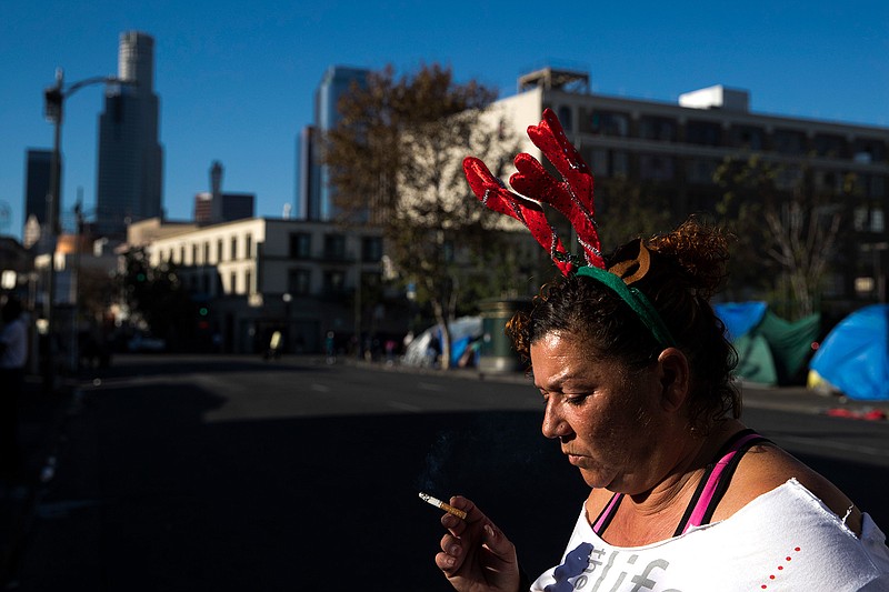 Wearing a Christmas headband, Grace Fernandez, who is homeless, smokes outside her tent in the Skid Row area of downtown Los Angeles, Friday, Dec. 1, 2017. "Holidays are just so much special. It should bring us altogether as one even if we are homeless," said Fernandez. The U.S. Department on Housing and Urban Development release of the 2017 homeless numbers are expected to show a dramatic increase in the number of people lacking shelter along the West Coast.