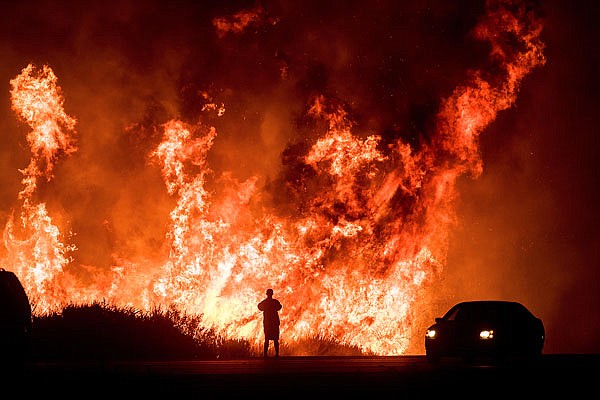 A motorist on Highway 101 watches flames from the Thomas fire leap above the roadway Wednesday north of Ventura, Calif.