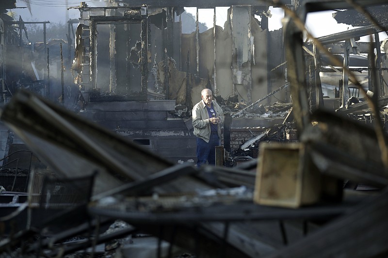 Dick Marsala looks through debris from his destroyed home after a wildfire roared through the Rancho Monserate Country Club Friday, Dec. 8, 2017, in Bonsall, Calif. The wind-swept blazes have forced tens of thousands of evacuations and destroyed dozens of homes in Southern California. (AP Photo/Gregory Bull)