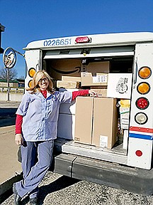 U.S. Postal Service carrier Dee Schubert stands outside her loaded postal delivery truck.