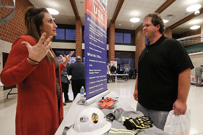 In this Thursday, Nov. 2, 2017, photo, a recruiter from a driller in the shale gas industry, left, speaks with an attendee at a job fair in Cheswick, Pa. On Friday, Dec. 8, 2017, the U.S. government issues the November jobs report. (AP Photo/Keith Srakocic)