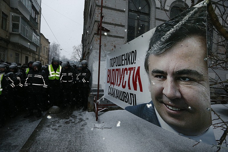 Police block supporters of former Georgian President Mikheil Saakashvili who are gathered outside the police station where Saakashvili was taken on Friday, Dec. 8, 2017, in Kiev, Ukraine, Sunday, Dec. 10, 2017. The words on a poster of Saakashvili reads 'Poroshenko, free Saakashvili!' Several thousand supporters of opposition leader Mikheil Saakashvili are rallying in the Ukrainian capital of Kiev to demand his release from jail. (AP Photo/Efrem Lukatsky)