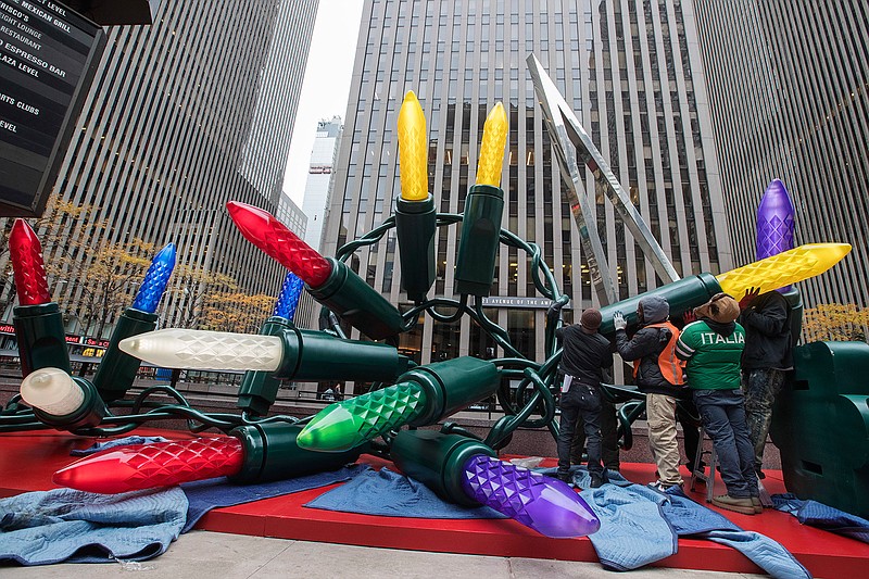 In this Saturday, Nov. 18, 2017, photo employees of the American Christmas company set up the Christmas display in front of 1221 Avenue of the Americas in Midtown Manhattan. American Christmas in suburban Mount Vernon is essentially a decorations attic for the nation's largest city and the surrounding area.