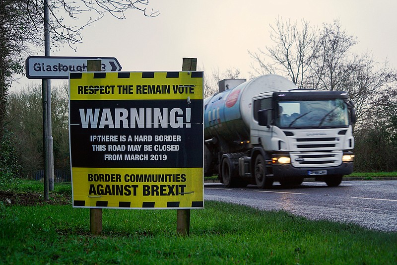 A truck drives past an "anti-Brexit" sign, set up by local activists, on a road on the outskirts of Middletown, Nothern Ireland, Britain, close to the border with Ireland, Thursday, Dec. 7, 2017. Britain and the bloc said Friday they had struck a deal ensuring that there will be no return to a "hard border" between Northern Ireland, which is part of the U.K., and EU member state Ireland after Brexit. That will not erase the fears of thousands who live or work across the currently invisible frontier.