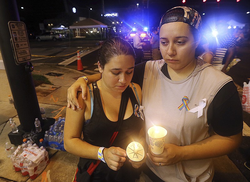 FILE - In this June 12, 2016, file photo, Sonia Parra, left, and Andrea Parra, who said they lost friends in the Pulse nightclub shooting, hold candles on the street corner near the nightclub in Orlando, Fla. In the five years since a gunman killed 20 children and six adults at the Sandy Hook elementary school in Newtown, Conn., the nation has seen a number of massacres topping the death toll from that shooting. (Curtis Compton/Atlanta Journal-Constitution via AP, File)