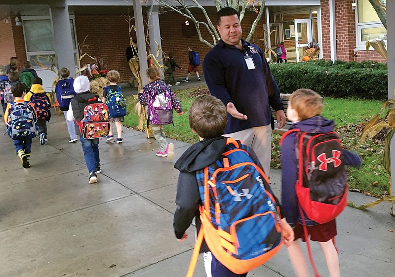 Campus monitor Hector Garcia greets students as they got off the bus Nov. 6 at the start of the school day at West Elementary School in New Canaan, Conn. Garcia and the district's other campus monitors—all former police or corrections officers—were among a wave of security officers hired in the aftermath of the deadly school shooting in nearby Newtown, Conn. on Dec. 14, 2012.