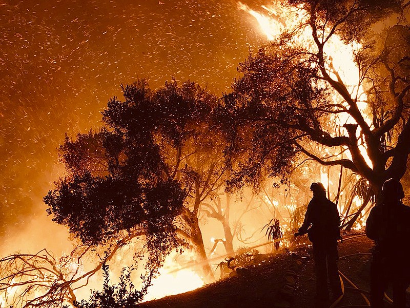 In this Sunday, Dec. 10, 2017, photo released by Santa Barbara County Fire Department firefighters knock down flames as they advance on homes atop Shepherd Mesa Road in Carpinteria, Calif. A flare-up on the western edge of Southern California's largest and most destructive wildfire sent residents fleeing Sunday, as wind-fanned flames churned through canyons and down hillsides toward coastal towns. Crews with help from water-dropping aircraft saved several homes as unpredictable gusts sent the blaze churning deeper into foothill areas northwest of Los Angeles that haven't burned in decades. New evacuations were ordered in Carpinteria, a seaside city in Santa Barbara County that has been under fire threat for days. (Mike Eliason/Santa Barbara County Fire Department)