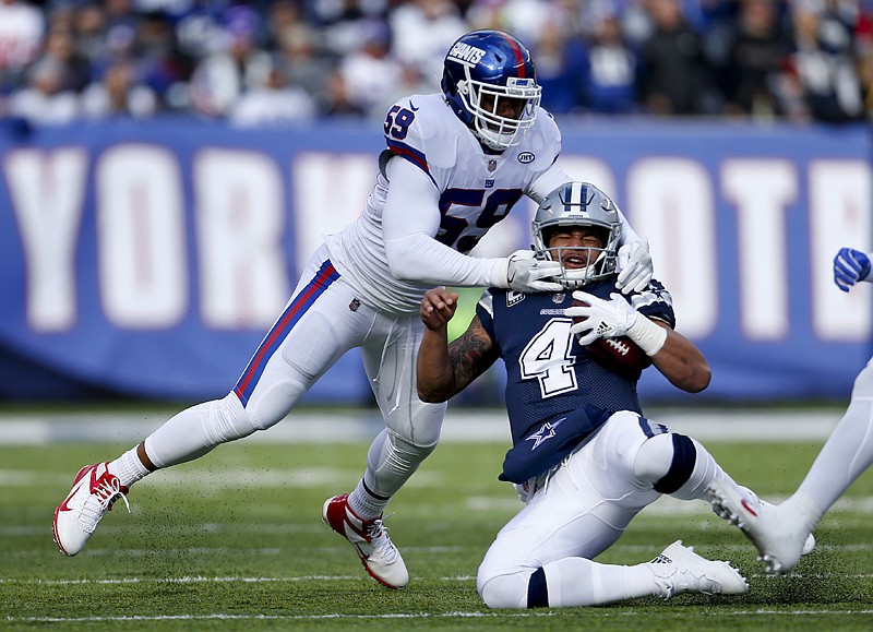 Dallas Cowboys quarterback Dak Prescott (4) slides as he takes a hit from New York Giants outside linebacker Devon Kennard (59) during the first quarter of an NFL football game Sunday in East Rutherford, N.J.