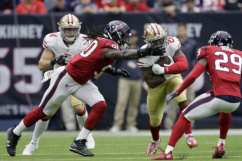 San Francisco 49ers running back Carlos Hyde (28) is grabbed by Houston Texans outside linebacker Jadeveon Clowney (90) during the first half of an NFL football game Sunday in Houston.