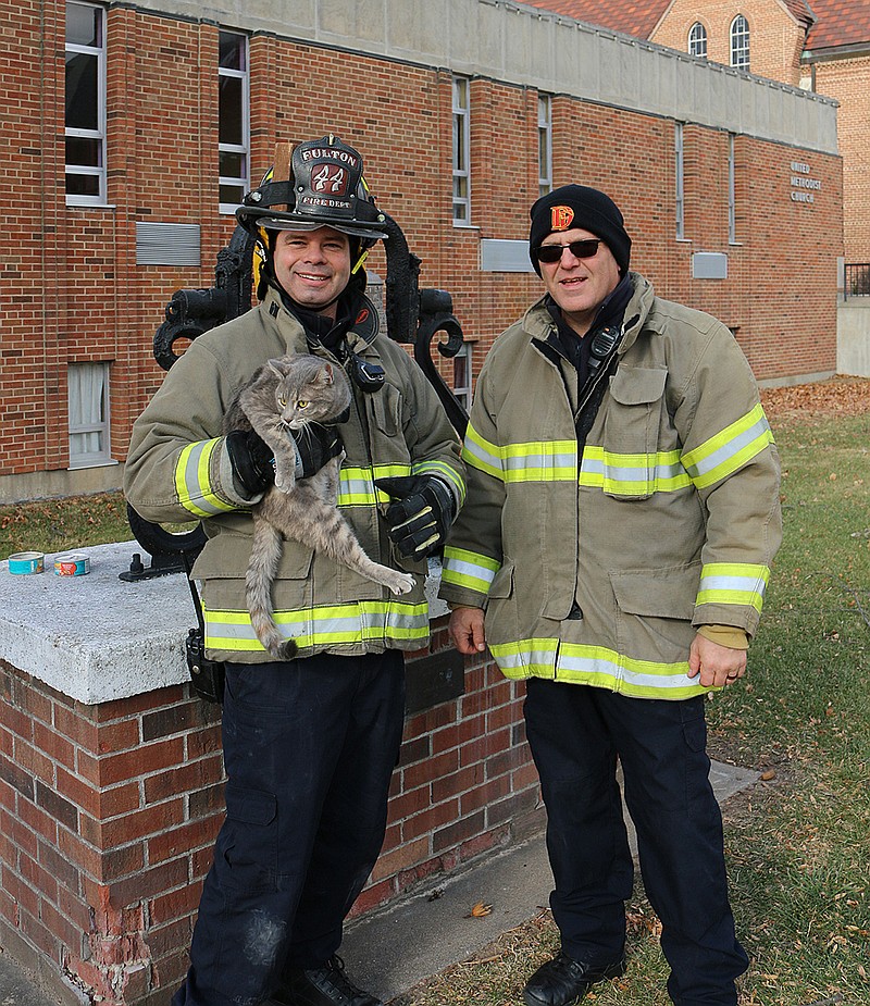 Firefighter Dennis Bacon (left) and Capt. Irving Garbison of the Fulton Fire Department rescued this friendly cat from high in a tree near the intersection of Court Street and St. Louis Avenue on Saturday. Pastor Aaron White was coming to an activity at Fulton Presbyterian Church and memorialized the rescue with his camera, calling it a 'classic act of mercy.'