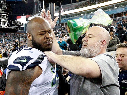 A Seahawks staff member tries to get defensive tackle Quinton Jefferson off the field as an object thrown from the stands hits them during the closing moments of Sunday's game against the Jaguars in Jacksonville, Fla.