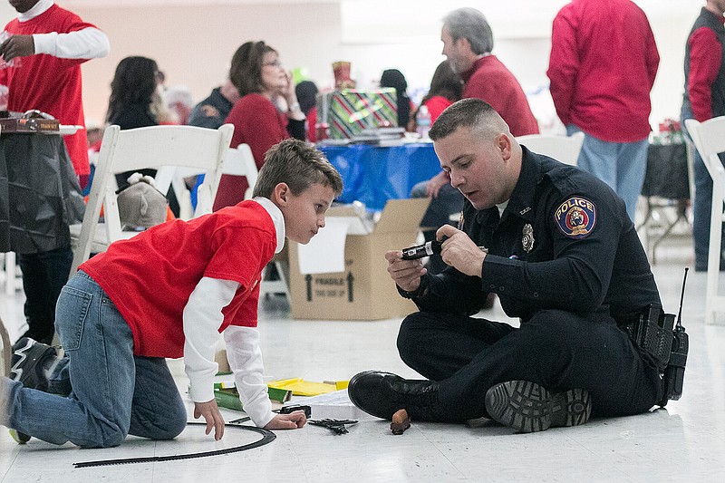 Officer Rick Cockrell helps Ari Castillo, 10, put together a railroad track Tuesday at the Barbara Gleboff Fine Arts Building at the Four States Fairgrounds. The Texarkana, Ark., Police Department met with Arkansas Baptist Children's Home and Watersprings Ranch to visit with children in a positive environment for the holidays. More than 140 children were able to dine and hang out with officers.