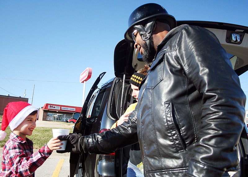 Emil Lippe/News Tribune
Hudson Patrick hands a cup of hot chocolate to Howard Booe during his hot cocoa for a cause sale outside of a local Hy-vee on Saturday, Dec. 16, 2017. Passersby donated money and toys to Hudson; proceeds from the sale will go to the food bank and Toys for Tots.