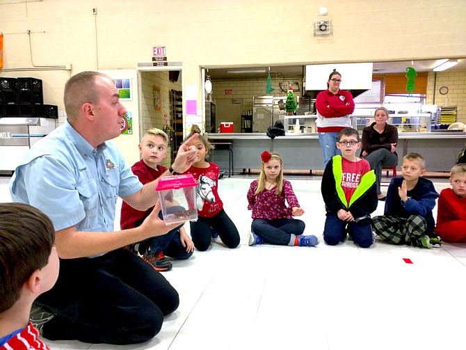 Sam Stewart, left, a naturalist with the Missouri Department of Conservation, introduces students at Bartley Elementary School to a milk snake. The brightly colored, nonvenomous snake was likely born earlier this year, he said.