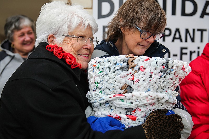 In this Thursday, Dec. 7, 2017 photo, Calvary Lutheran Church volunteer Doris Wendland braces against the cold outside with Mosaic client Margaret Webb while they present grocery-bag mats they created at Project Dignidad, in San Angelo, Texas.