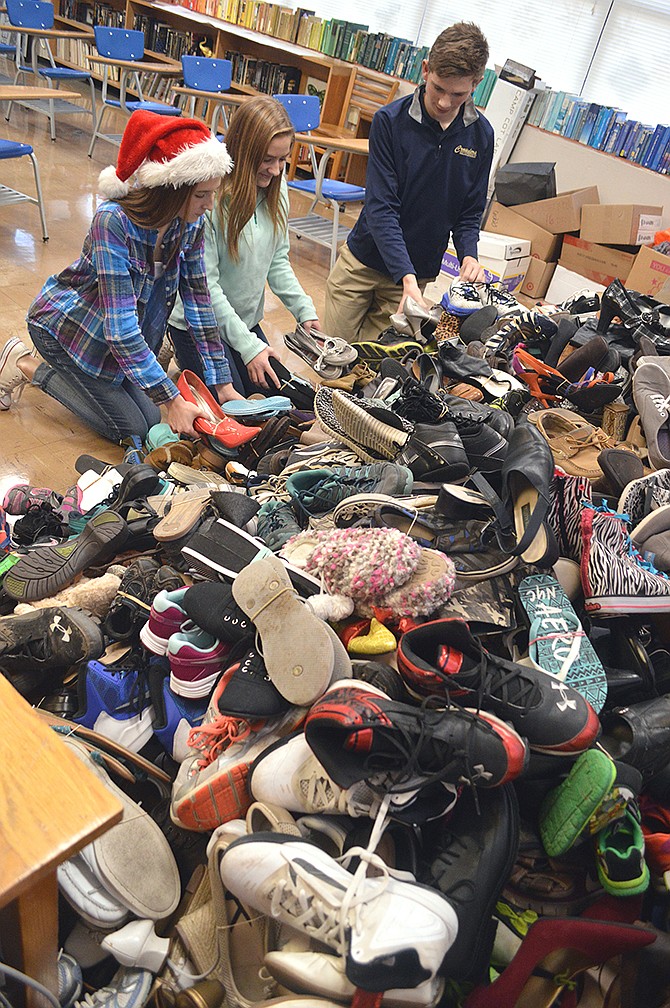 Mark Wilson/News Tribune
Helias High School sophomores Marcy Wicks, Katherine Schrimpf and Tevin Goose sort through more than 1,000 pairs of donated shoes Friday in a project for their English class where students learned about the Holocaust.