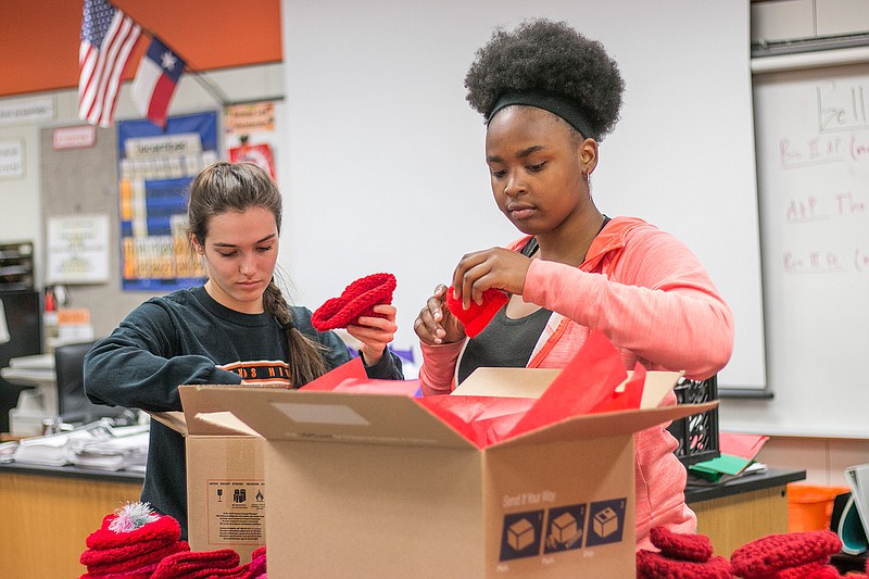 Junior Brittany Kile and freshman Shakira Sanders prepare red hats for shipping Friday at Texas High School. The students are part of a crocheting enrichment class at THS and have chosen to be part of an American Red Heart Association fundraiser to send red hats to hospitals celebrating American Heart Month in February. 