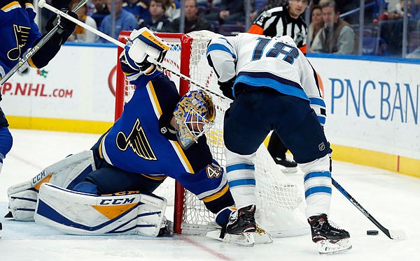 Blues goalie Carter Hutton watches as the Jets' Bryan Little controls the puck behind the net during the first period of Saturday's game in St. Louis.