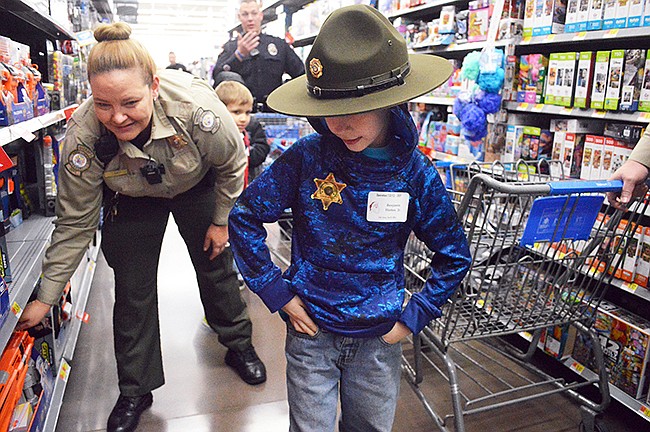 Benjamin Horton Jr. and Deputy Sheriff Julie Dacy shop for a Raptor Strike toy while on a holiday spending spree during Operation Take Our Youth Shopping on Saturday morning at Walmart Supercenter.