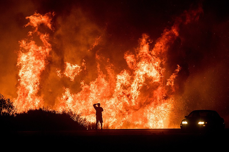 A motorist on Highway 101 watches flames from the Thomas fire leap above the roadway north of Ventura, Calif., on Wednesday, Dec. 6, 2017.