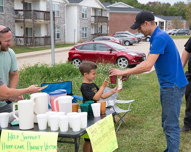 Hudson Patrick serves a cup of lemonade to Jake Biermann at his stand Sept. 9. The 6-year-old was helping raise money for relief efforts from the devastation caused by Hurricane Harvey.