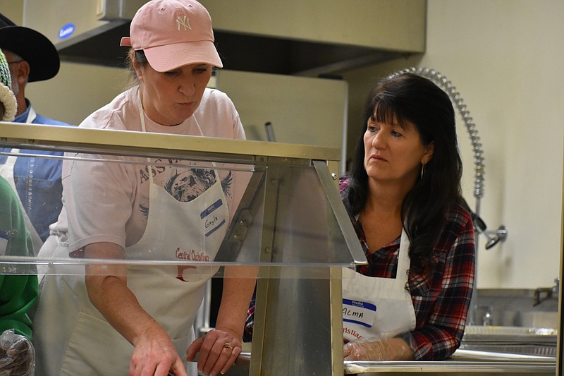 Gayla Strout, left, and Alma Weed, serve plates of food to people Monday at the Central Christian Church (Disciples of Christ). Volunteers served 353 meals to people who didn't have a way to prepare a meal, the homeless and the needy. 
