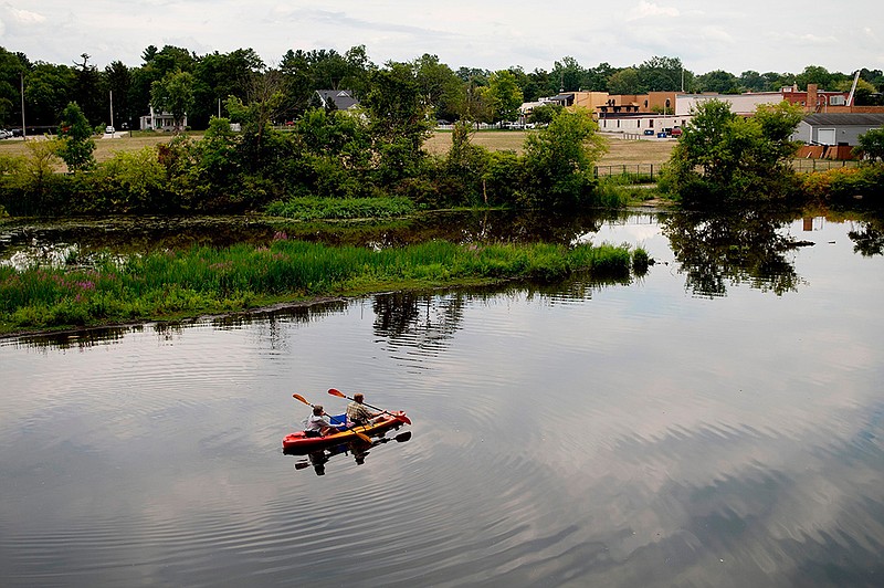 In this Monday, Aug. 14, 2017 file photo, a couple kayak on the Rogue River adjacent to where Wolverine World Wide's tannery once stood, in Rockford, Mich. The Michigan Department of Environmental Quality is investigating the connection between old waste drums in the area and an old Wolverine World Wide tannery waste dump nearby. Some private wells in the area have tested positive for elevated levels of per- and polyfluoroalkyl substances called PFAS, also called perfluorinated chemicals, or PFCs. The DEQ says Wolverine dumped sludge containing the chemicals in unlined trenches back in the 1960s. The well contamination was discovered this year. 