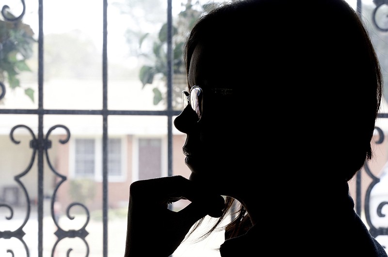 In this photo taken Friday, Dec. 15, 2017 Veronica, a victim of sexual assault 13 years ago sits in front of a large window at her home in Fayetteville, N.C. Veronica's rape kit from the incident was among 333 kits that Fayetteville police had thrown away. Years after the kits were discarded, Fayetteville police have been working with a crisis group to call the victims and tell them what happened. (AP Photo/Gerry Broome)