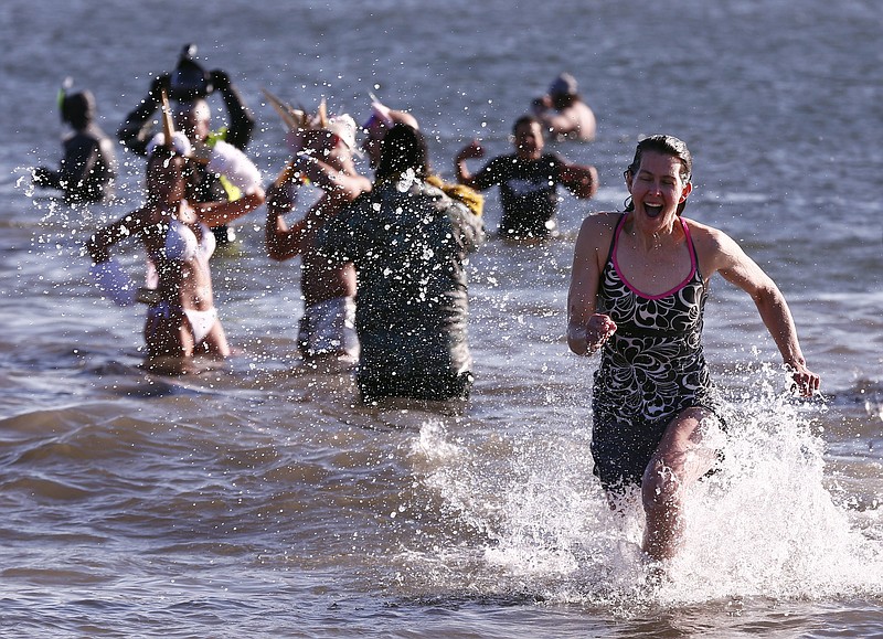 People taking part in Coney Island's annual New Year's Day Polar Plunge frolic in the surf in New York, on Monday, Jan. 1, 2018. Temperatures hovered at about 17 degrees (-8 Celsius) for the annual tradition that began in 1903. (AP Photo/Peter Morgan) .