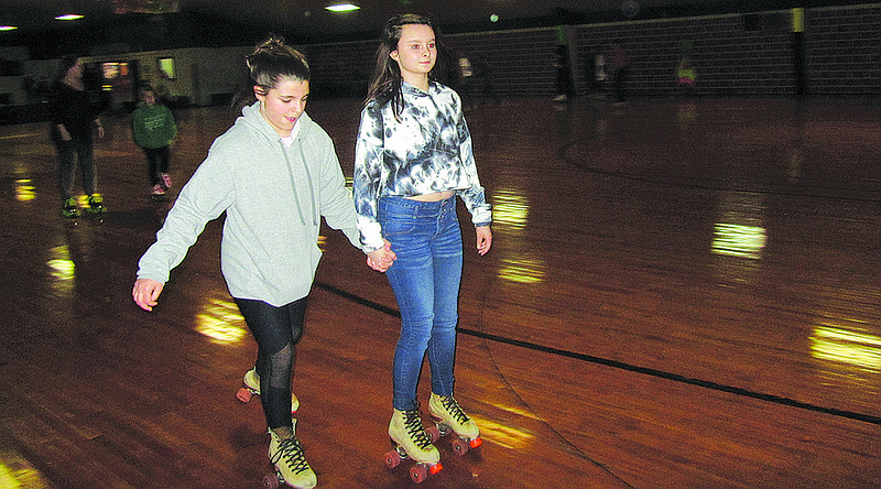 Lilly Broyles, left, and Abby Holland skate together Sunday night at Sk8 Zone's annual New Year's Eve party.