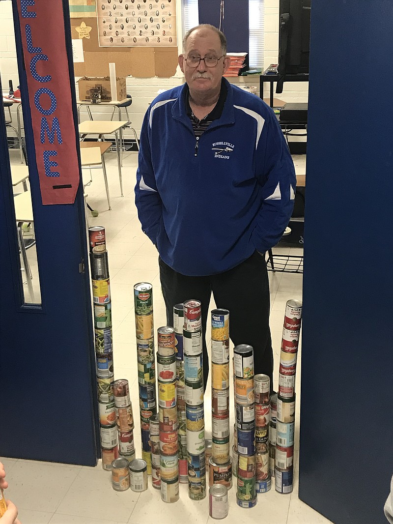 Russellville Middle School science teacher Tom Backes stands in his classroom doorway, which was blocked by cans of food collected by sixth-grade students. Backes decided not to attempt the hurdle and the students were awarded a day off from his class.
