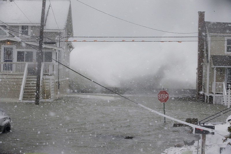 An Atlantic Ocean wave crashes into the seawall between two houses on Ocean Avenue Thursday, Jan. 4, 2018, in Scituate, Mass. The National Weather Service has issued a blizzard warning for Thursday that extends from eastern Long Island north to coastal New Hampshire and Maine. Most of the rest of southern New England is under a winter storm watch. 