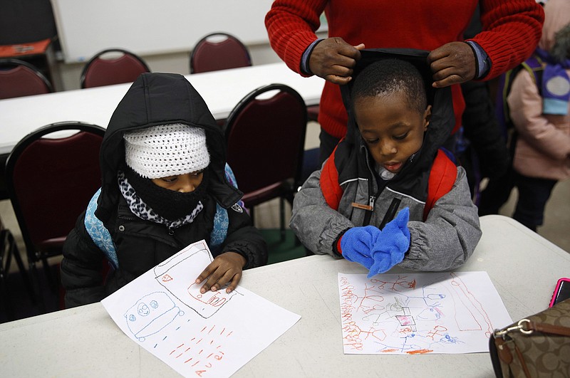 In this Jan. 9, 2018 photo, teacher Loraine Wilson, top right, helps bundle up pre-kindergarten students as they wait to be picked up at the end of a school day at Lakewood Elementary School in Baltimore. The recent spell of cold weather exposed the poor state of school buildings in many big-city East Coast districts, including Baltimore. Lakewood students were sent back home Monday morning after pipes burst just as buses began dropping youngsters off. The school was able to reopen for classes Tuesday. (AP Photo/Patrick Semansky)