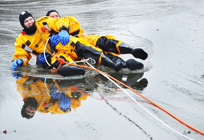 Firefighters Jason Karr, left, and Quentin Combs are pulled out of the water Tuesday during Jefferson City Fire Department training in McKay Lake. For the next few days, firefighters will practice tactics for still water ice rescue. Each shift practices being the victim and the rescuer. 