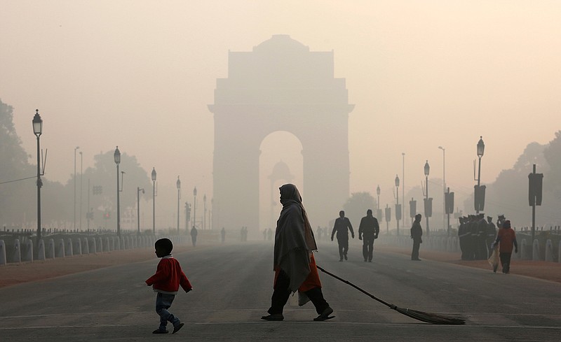 An Indian municipal worker and her child walk in front of India Gate, the landmark war, in New Delhi, India, Tuesday, Jan. 9, 2018. 