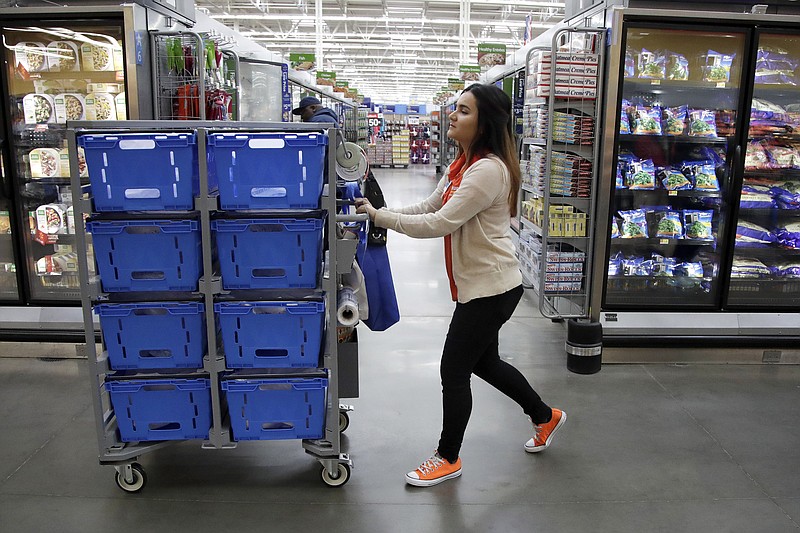 In this Thursday, Nov. 9, 2017, photo, Laila Ummelaila, a personal shopper at the Walmart store in Old Bridge, N.J., pushes a cart with bins as she shops for online shoppers. On Thursday, Jan. 11, 2018, Walmart announced it is boosting its starting salary for U.S. workers to $11 an hour, giving a one-time $1,000 cash bonus to eligible employees and expanding its maternity and parental leave benefits. (AP Photo/Julio Cortez)