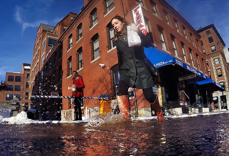 A pedestrian splashes through a puddle of snowmelt as temperatures climbed above freezing, Wednesday, Jan. 10, 2018, in Portland, Maine. The temperatures in the upper 30s were a welcome relief following a long stretch of sub-zero weather. 