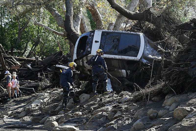 Members of the Los Angeles County Fire Department Search and Rescue crew work on a car trapped under debris in Montecito, Calif., Wednesday, Jan. 10, 2018. Dozens of homes were swept away or heavily damaged and several people were killed Tuesday as downpours sent mud and boulders roaring down hills stripped of vegetation by a gigantic wildfire that raged in Southern California last month.