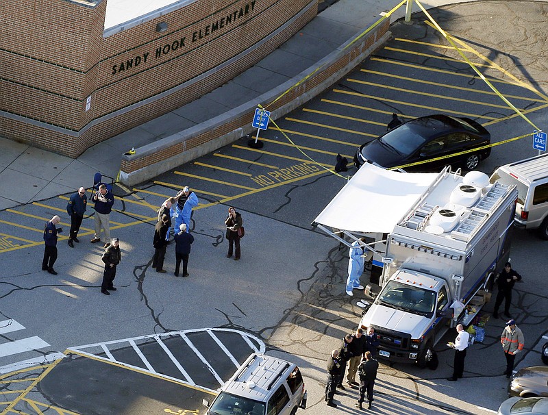 FILE - In this Dec. 14, 2012, file photo, officials stand outside of Sandy Hook Elementary School after a shooting in Newtown, Conn. Connecticut State Police are planning to release a report assessing the agency’s response to the 2012 massacre at Sandy Hook Elementary School. The after-action report is expected Friday, Jan. 12, 2018. (AP Photo/Julio Cortez, File)