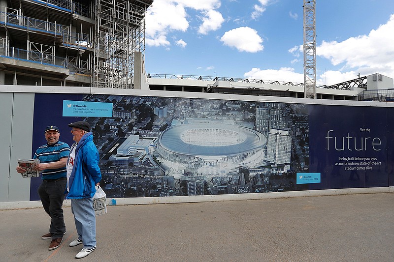  In this May 14, 2017, file photo, football fans smile as they pass a poster showing the plans for the new stadium, in front of construction work at White Hart Lane stadium in London, before a match between Tottenham Hotspur and Manchester United. The Oakland Raiders will host the Seattle Seahawks in the first NFL game at the new London stadium of English Premier League club Tottenham. The game will be played in week six of the season on Oct. 14. 