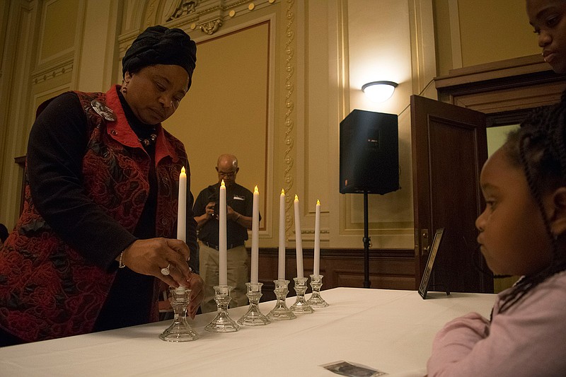 Beverly Webb places a candle in memory of Dr. Martin Luther King Jr. during the 17th annual African American Voice: An Evening of Performance with Special Moments for Dr. Martin Luther King Jr. on Friday at the Regional Arts Center. (Photo by Tiffany Brown)
