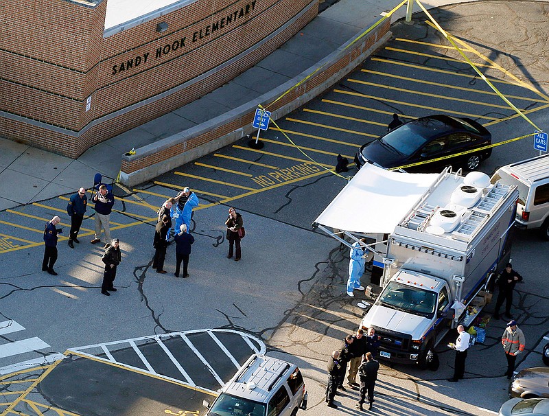 In this Dec. 14, 2012, file photo, officials stand outside of Sandy Hook Elementary School after a shooting in Newtown, Conn. Connecticut State Police are planning to release a report assessing the agency's response to the 2012 massacre at Sandy Hook Elementary School.