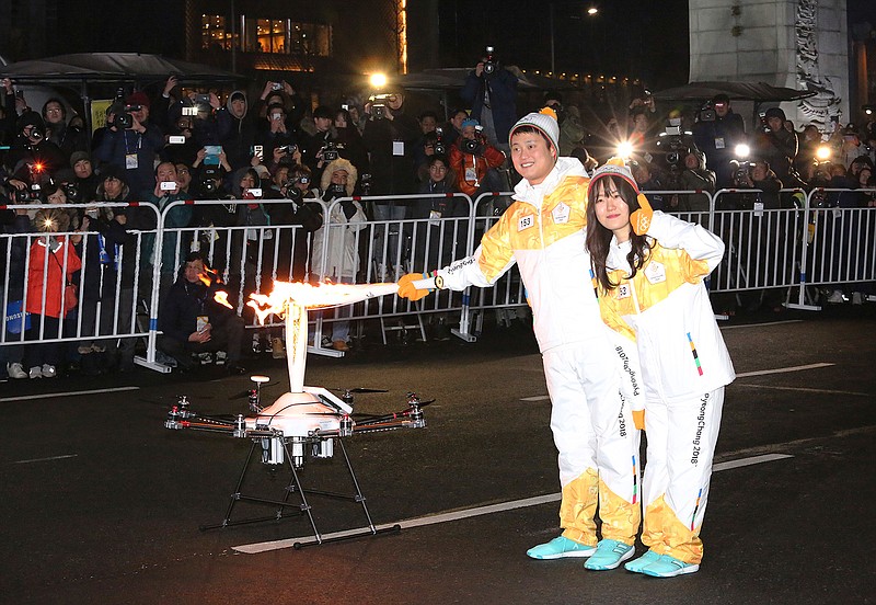 Torch bearers pose as they pass the Olympic flame to a drone during the Olympic Torch Relay in Seoul, South Korea, Saturday, Jan. 13, 2018. South Korea said Saturday that North Korea proposed that their talks next week address a North Korean art troupe's visit to the Pyeongchang Winter Olympics in the South, rather than the participation of the nation's athletes. 