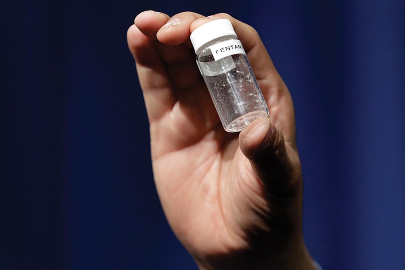 A reporter holds up an example of the amount of fentanyl that can be deadly after a news conference about deaths from fentanyl exposure, at DEA Headquarters in Arlington Va., Tuesday, June 6, 2017. 